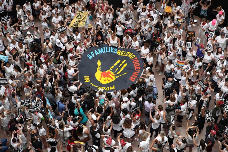 An aerial shot of protesters holding a banner reading #FamiliesBelongTogether.